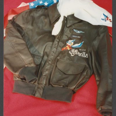 Charlyne Creger's brown bomber jacket with diamond wings and Fifinella emblems, and white scarf with an image of Fifinella with part of an American flag visible in the background.